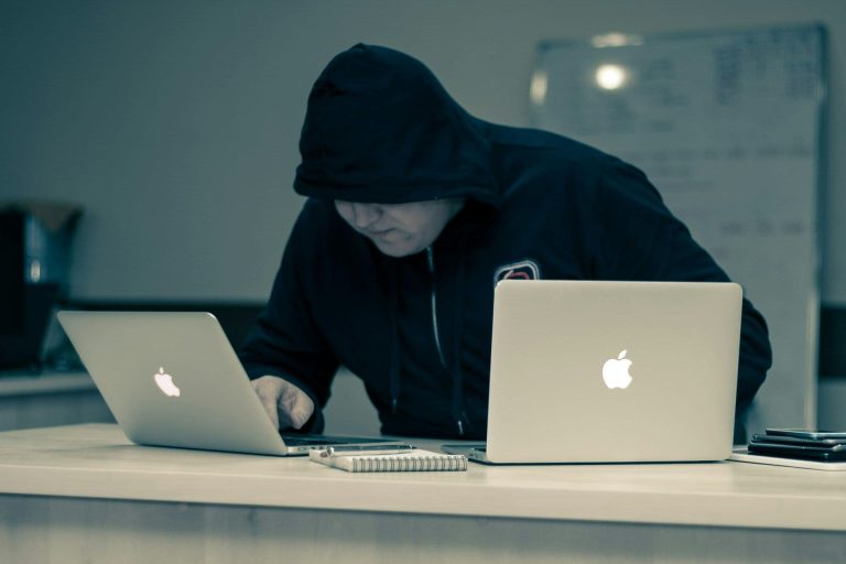 Hacker working on two laptops (Azamat E/Unsplash)