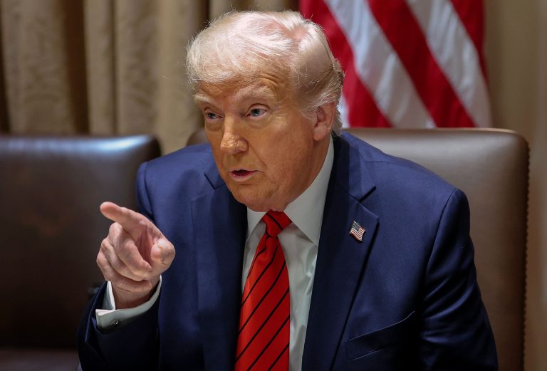 A seated President Donald Trump points a finger off camera.