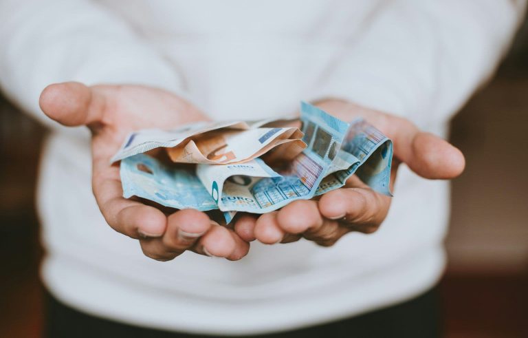 Lending money, bills on a person's hands (Christian Dubovan/Unsplash)