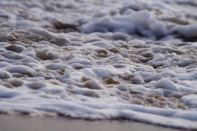 Photo of wave froth on a sandy beach. (justus_joseph/Pixabay)