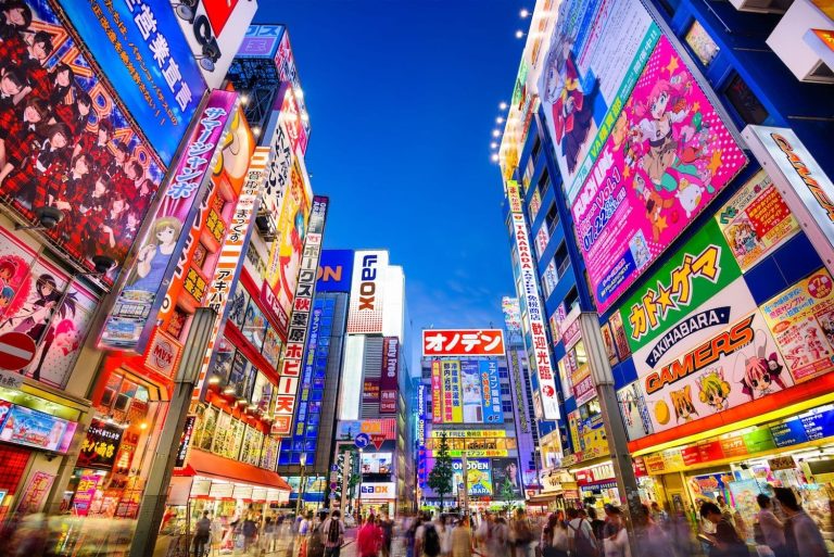 Crowds pass below colorful signs in Tokyo's Akihabara district.
