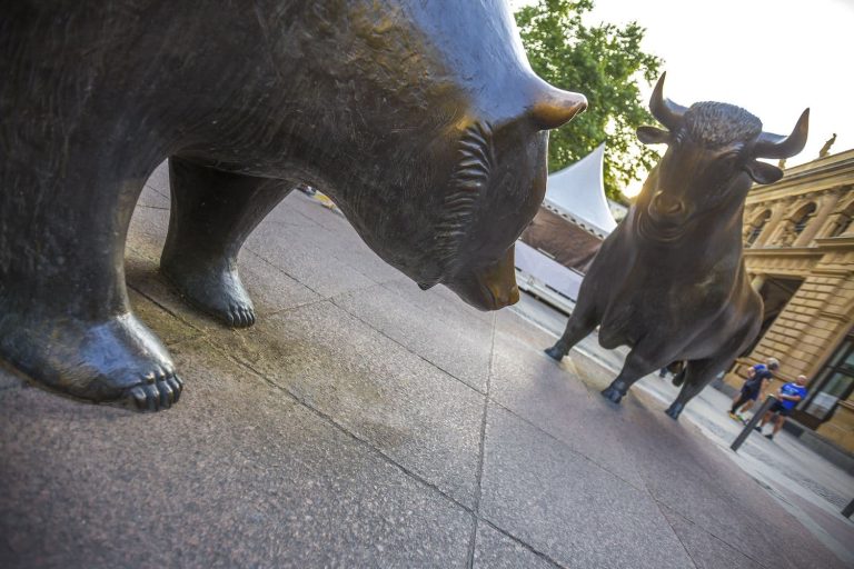 Metal castings depicting bear and a bull stand on the street.