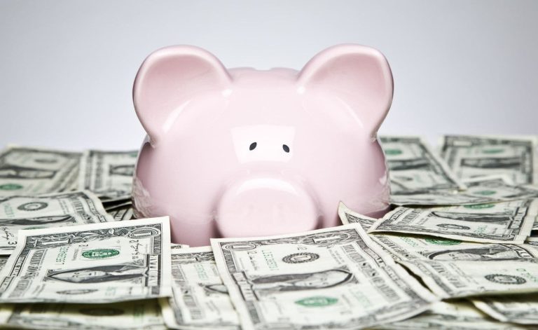 A piggy bank surrounded by dollar bills.